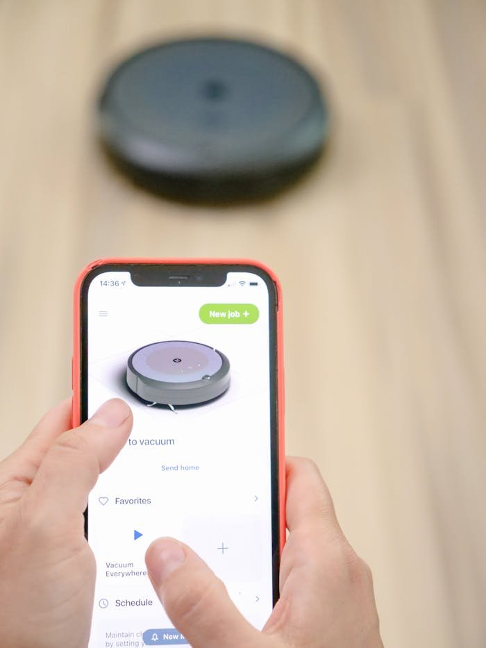 User operates robotic vacuum via smartphone app, showcasing smart home technology.